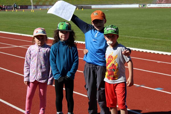 Eine Vierer-Gruppe von Grundstufenkindern, ein Junge hält den Laufzettel des Sportfestes hoch.