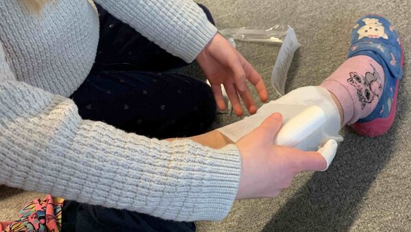 Kinderbein, an dem ein Verband angelegt wird.