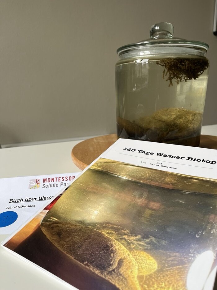 KPA Werkstück - Glas mit Wasser und Heft mit der Überschrift 140 Tage Wasserbiotop