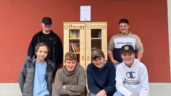 Die Schüler, die den Bücherschrank an der Montessori-Schule Passau, gebaut haben, stehen vor diesem.