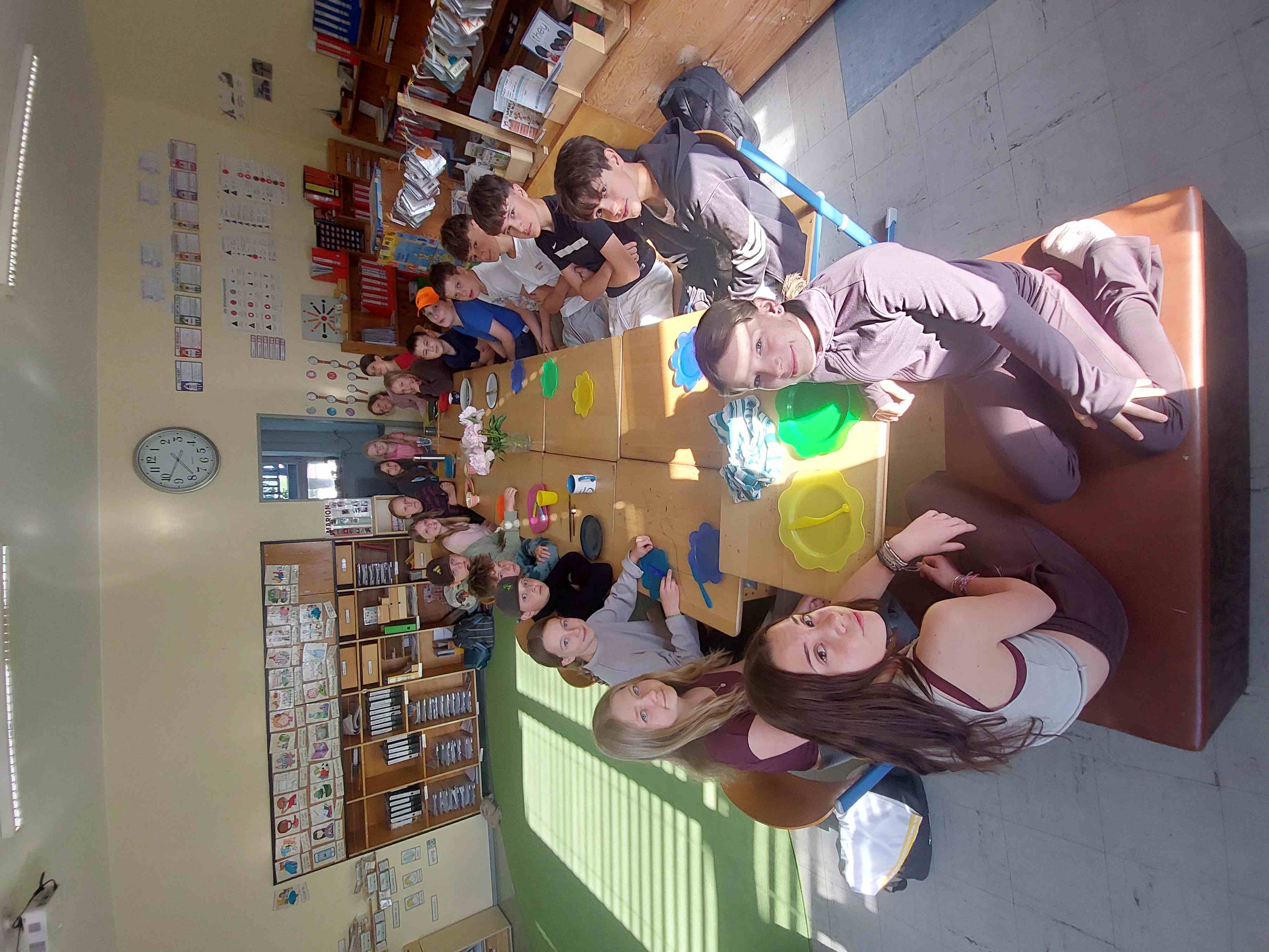 Kinder sitzen zusammen beim Frühstück an einem langen Tisch in einem Klassenzimmer